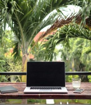 A laptop placed on the table with the green trees in background