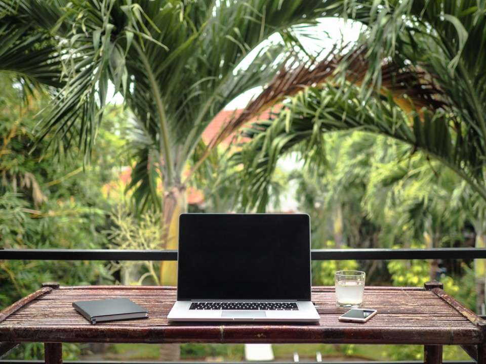 A laptop placed on the table with the green trees in background
